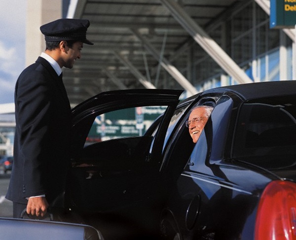 Chauffeur Holding a Suitcase and Opening a Door For a Mature Businessman