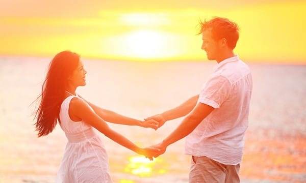 Romantic couple lovers holding hands at beach sunset. Happy mult